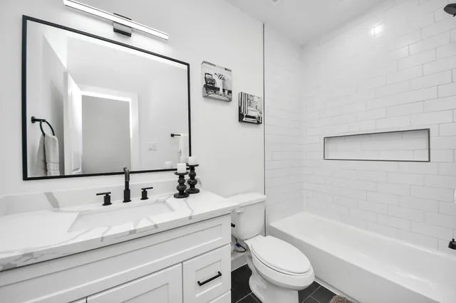 a bathroom with a granite countertop sink a toilet and a bathtub