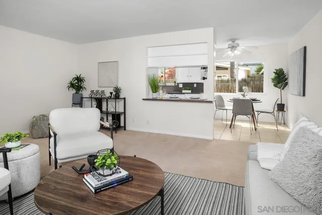 a living room with furniture kitchen view and a large window