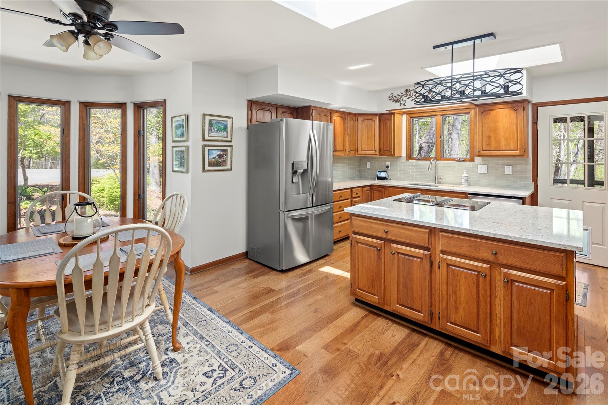 119 Rome Court Lake Lure, NC 28746 - Photo 8 of 31 a kitchen with stainless steel appliances granite countertop a refrigerator a sink dishwasher a dining table and chairs with wooden floor