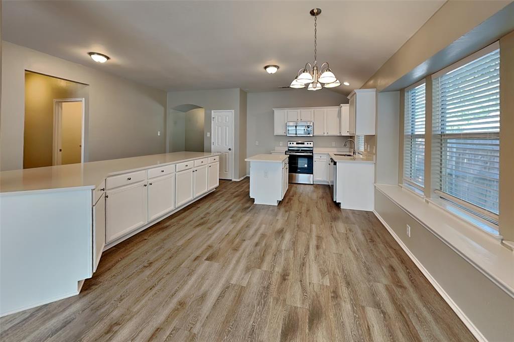 7016 Raintree Way Denton, TX 76210 - Photo 4 of 18 a large kitchen with granite countertop a large counter top space appliances and cabinets