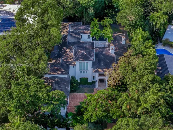 an aerial view of a house with a yard and large trees