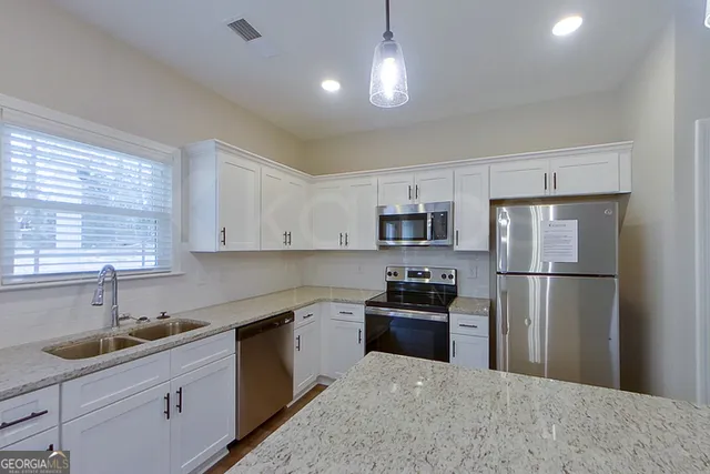 a kitchen with stainless steel appliances granite countertop a refrigerator sink and stove