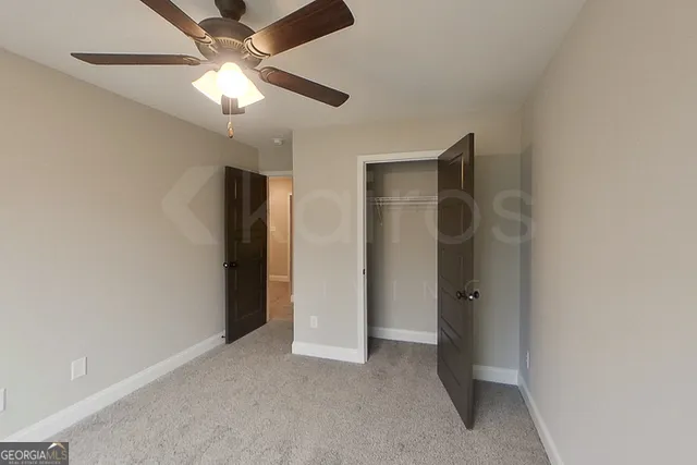an empty room with closet and a ceiling fan