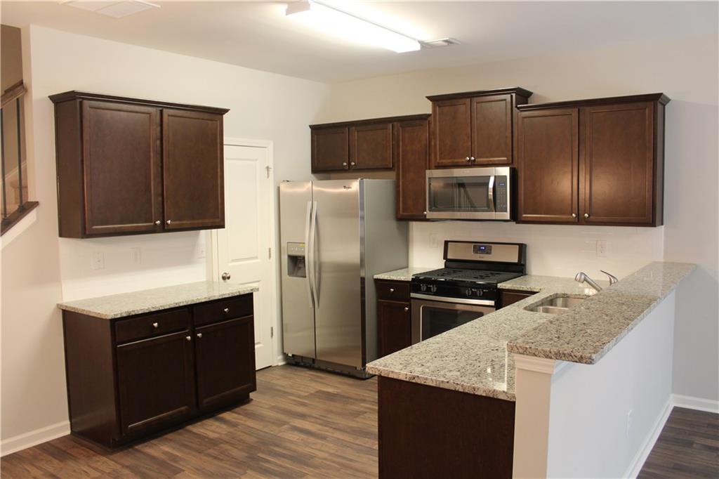 4741 Beacon Ridge Lane Flowery Branch, GA 30542 - Photo 4 of 15 a kitchen with granite countertop stainless steel appliances and wooden cabinets