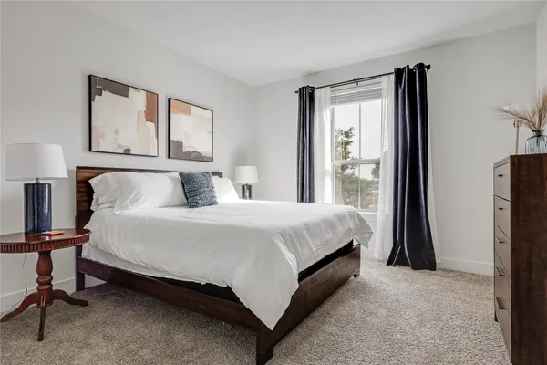 a bedroom with a bed lamp and a large window