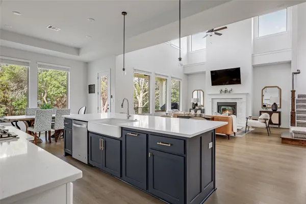 a open kitchen with stainless steel appliances granite countertop a stove top oven a sink dishwasher a dining table and chairs with wooden floor