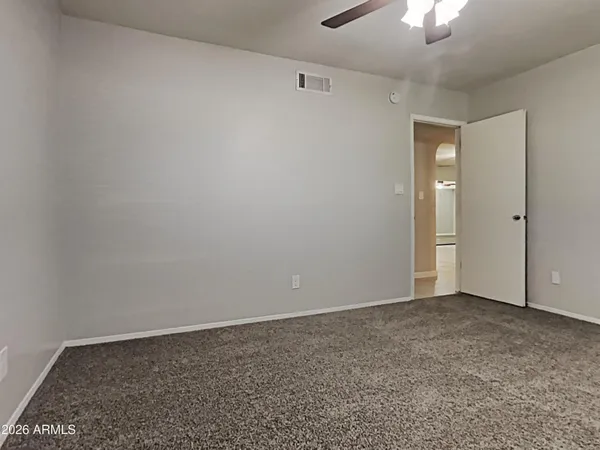a view of an empty room and chandelier fan