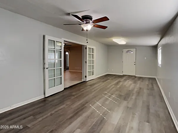 a view of an empty room with wooden floor and a ceiling fan