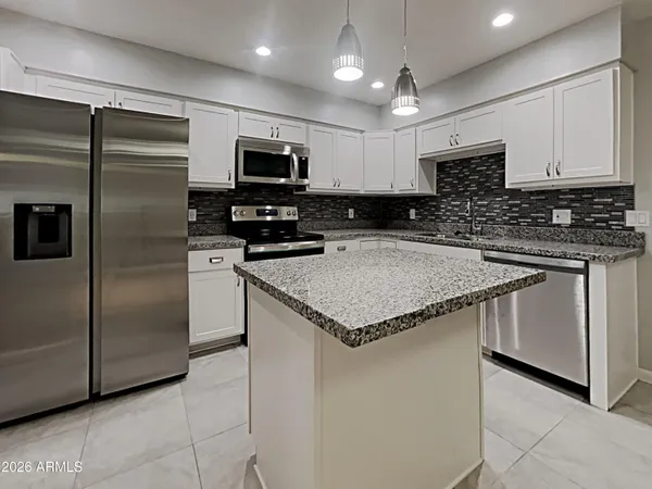 a kitchen with stainless steel appliances granite countertop a sink a microwave a refrigerator and a stove