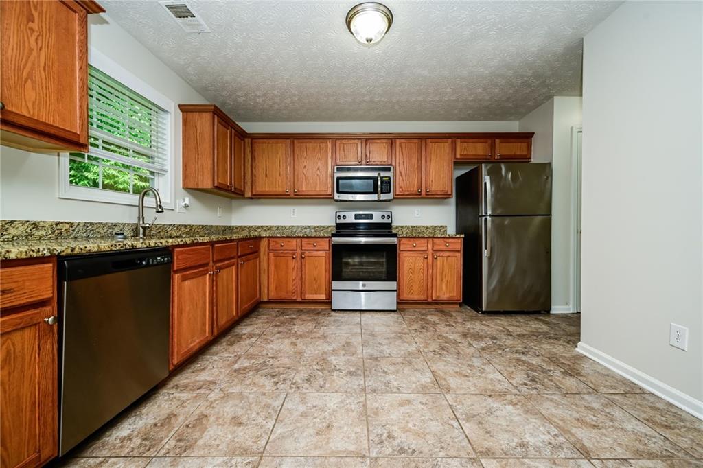 4468 Abram Way Conley, GA 30288 - Photo 4 of 23 a kitchen with stainless steel appliances granite countertop a stove a sink dishwasher and a refrigerator