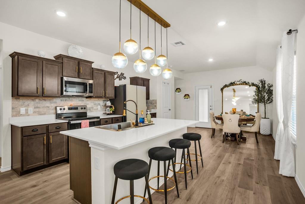 608 Daybreak Lane Lavon, TX 75166 - Photo 15 of 36 a kitchen with stainless steel appliances a stove top oven a refrigerator a sink dishwasher a dining table and chairs with wooden floor