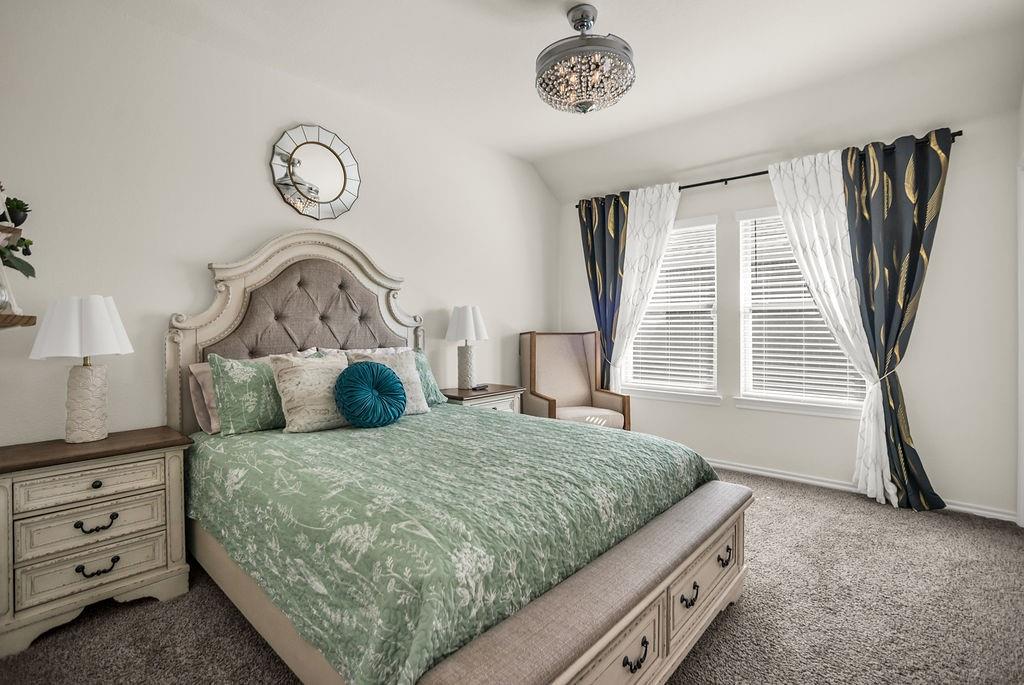 608 Daybreak Lane Lavon, TX 75166 - Photo 20 of 36 a bedroom with a bed and a chandelier