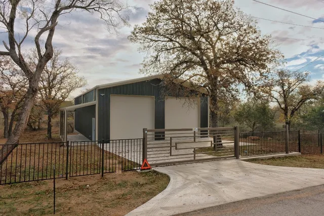 a view of house with wooden fence and large trees