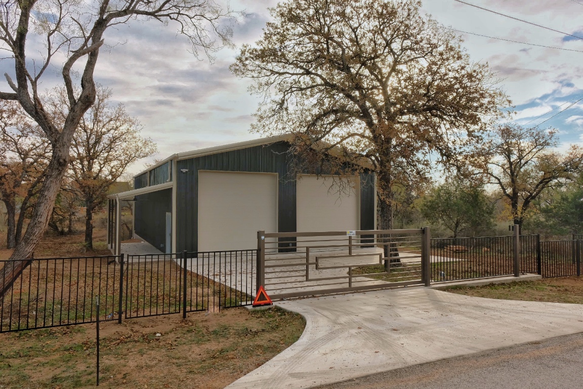 a view of house with wooden fence and large trees