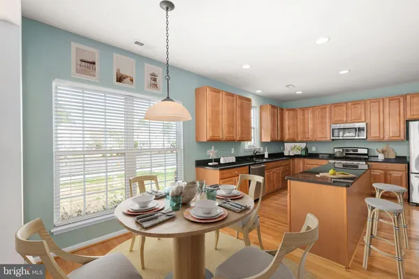 a kitchen with stainless steel appliances granite countertop a stove a refrigerator a kitchen island a table and chairs