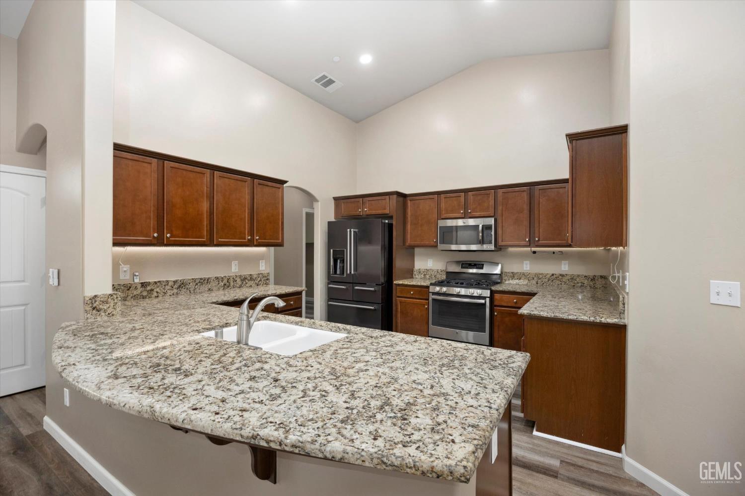 Undisclosed Address Bakersfield, CA 93314 - Photo 18 of 42 a kitchen with kitchen island granite countertop a sink stove and refrigerator