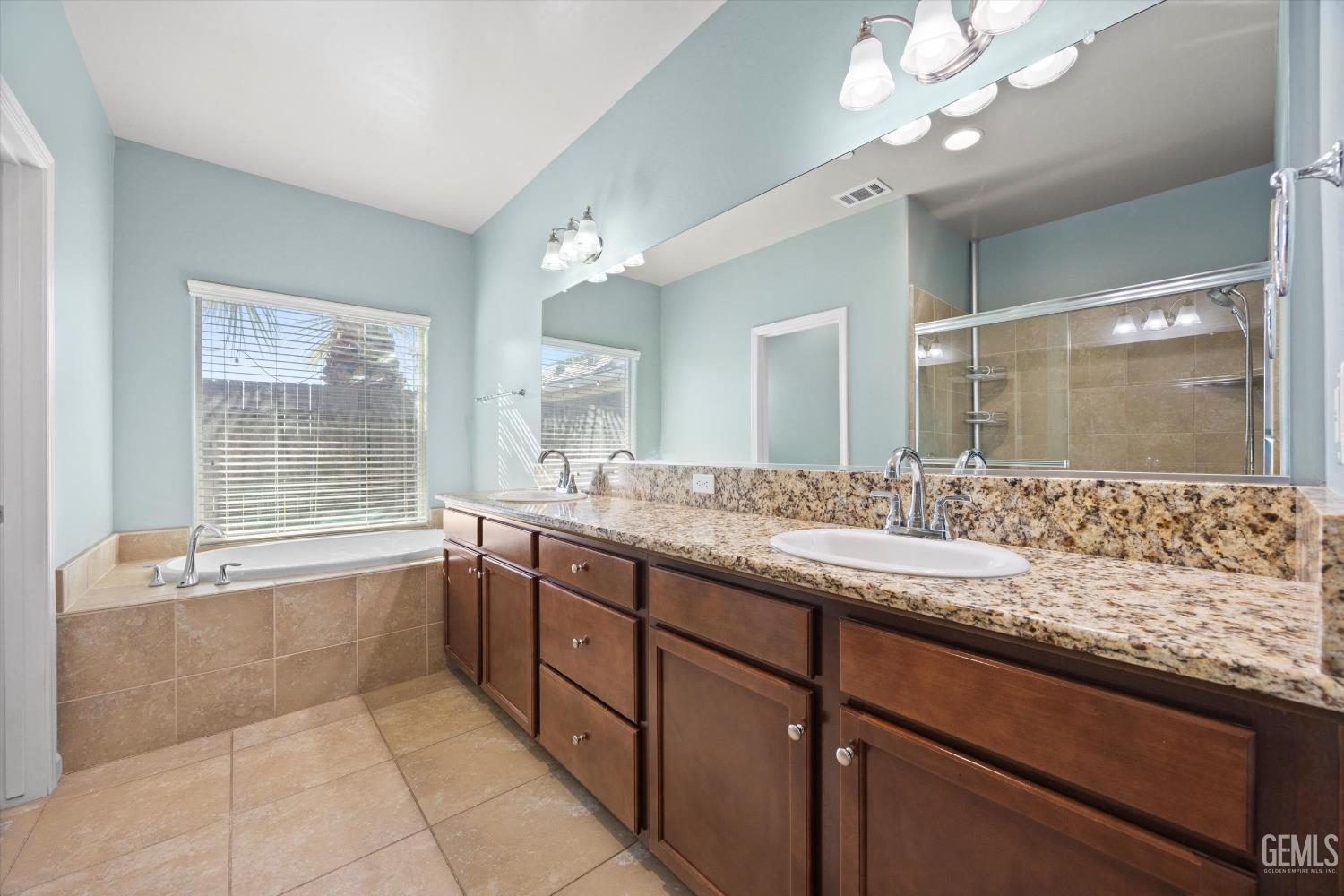 Undisclosed Address Bakersfield, CA 93314 - Photo 25 of 42 a bathroom with a granite countertop sink a large mirror and a bathtub with shower