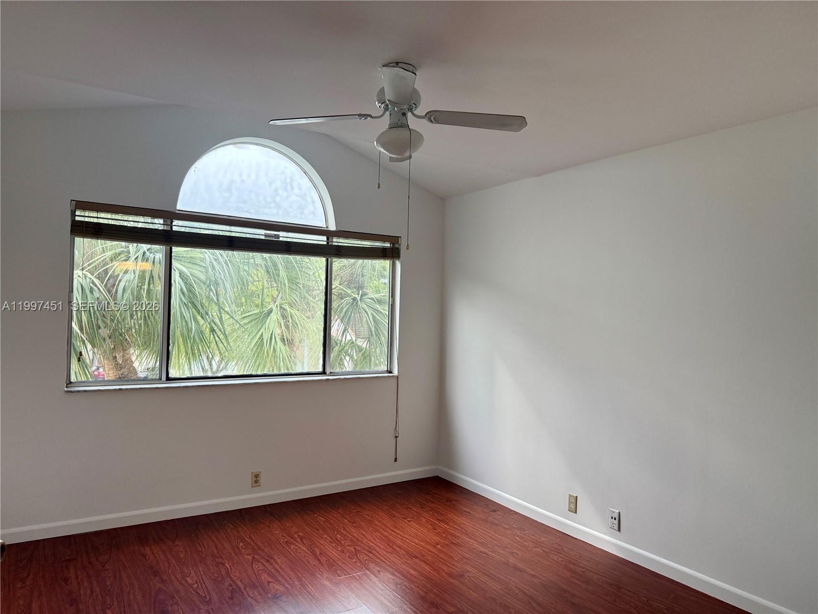 9435 Southwest 140th Court, Unit 9435 Miami, FL 33186 - Photo 29 of 33 an empty room with wooden floor fan and windows