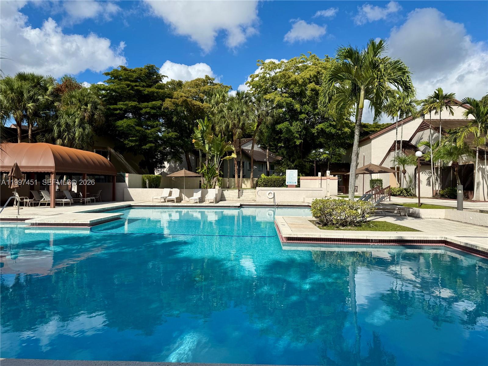 9435 Southwest 140th Court, Unit 9435 Miami, FL 33186 - Photo 5 of 33 a view of swimming pool with lawn chairs under an umbrella