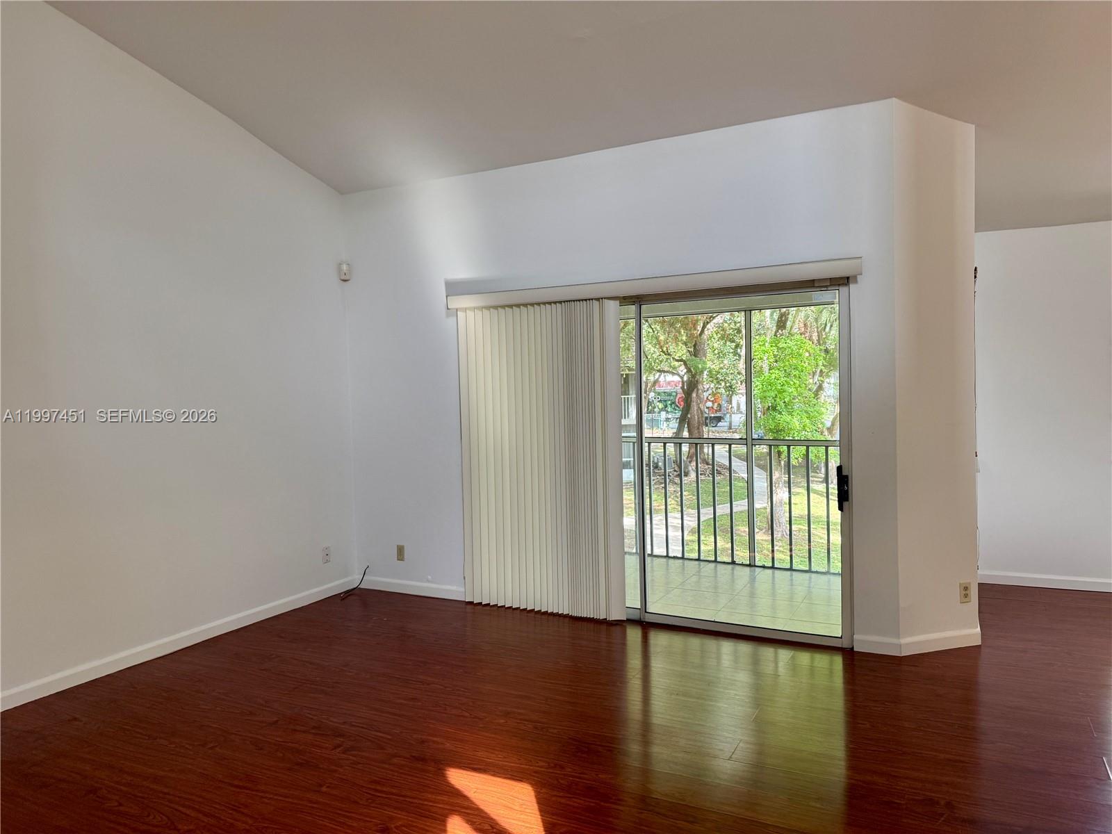 9435 Southwest 140th Court, Unit 9435 Miami, FL 33186 - Photo 8 of 33 a view of an empty room with wooden floor and a window
