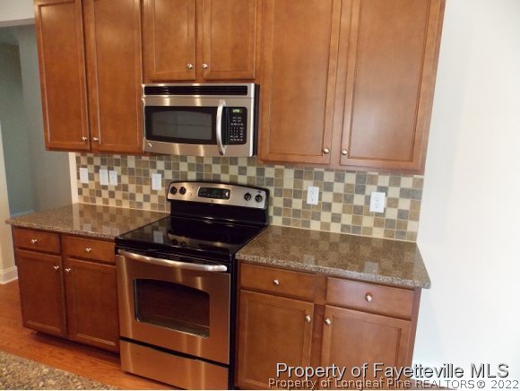 344 Kerr Lake Road Aberdeen, NC 28315 - Photo 5 of 25 a kitchen with stainless steel appliances granite countertop wooden cabinets stove top oven and microwave