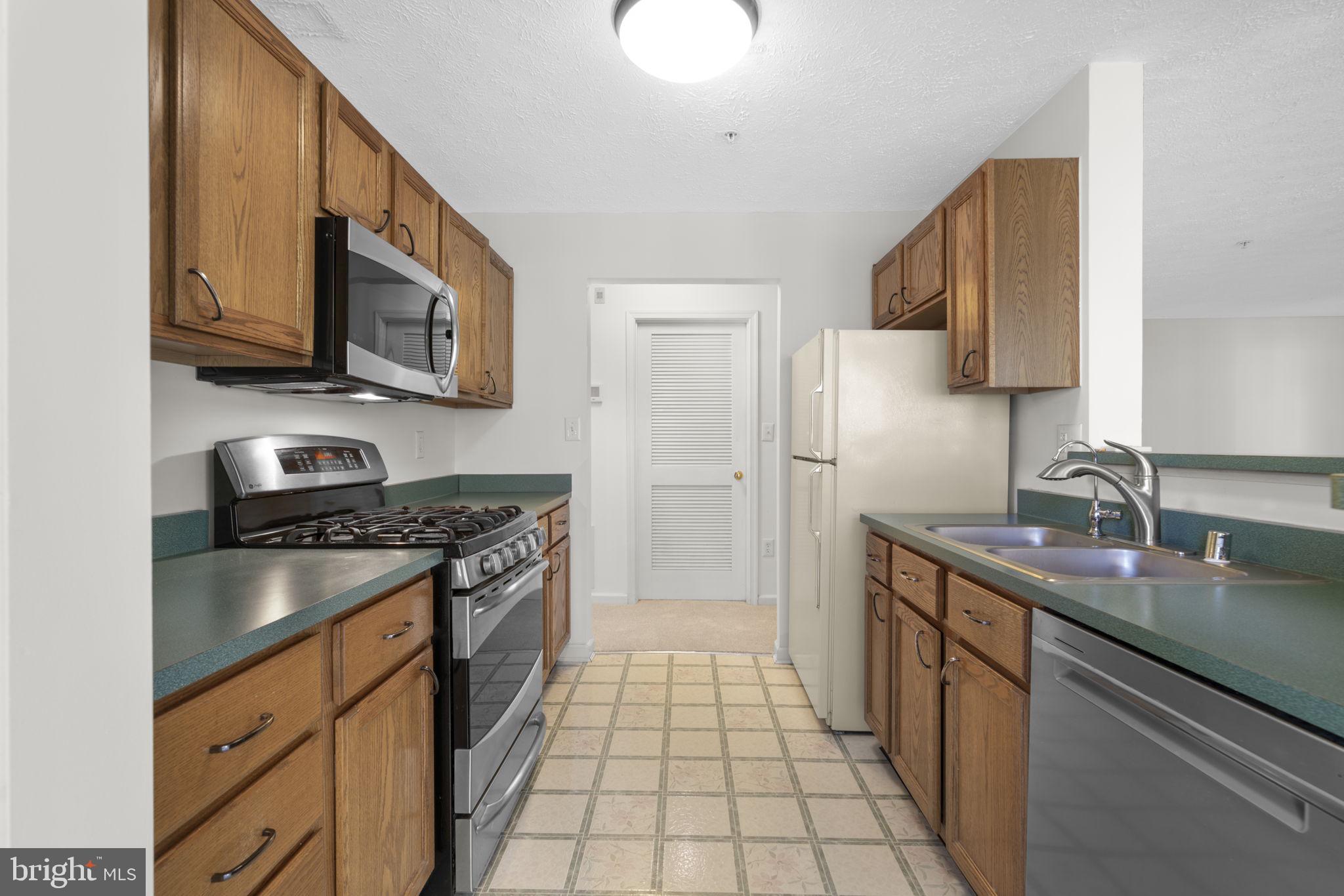 2444 Blue Spring Court, Unit 203 Odenton, MD 21113 - Photo 13 of 36 a kitchen with stainless steel appliances granite countertop a stove a sink and a microwave