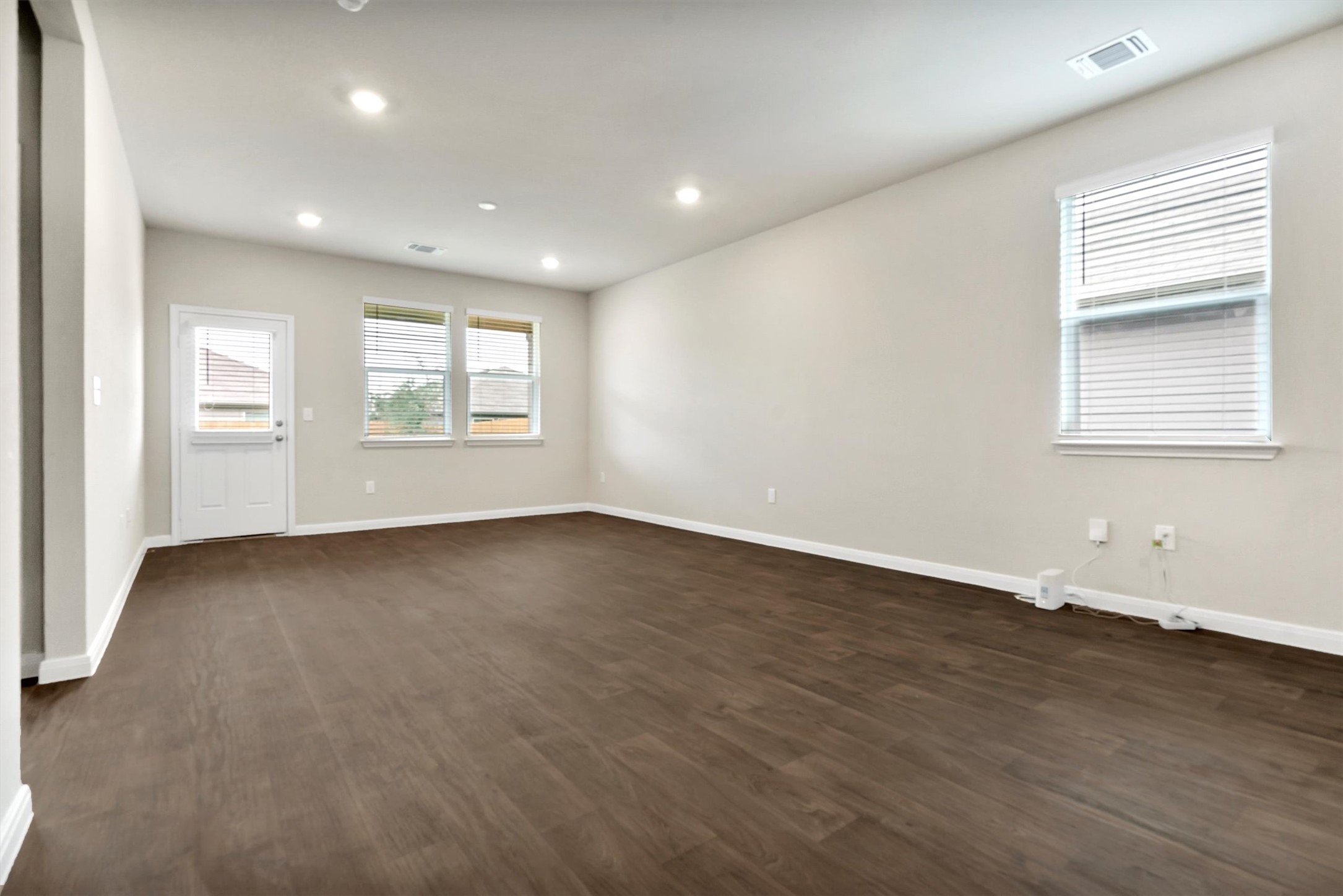 2909 Tweedy Trail Pflugerville, TX 78660 - Photo 7 of 27 A spacious room offers rich wood flooring, abundant natural light, and modern recessed lighting.