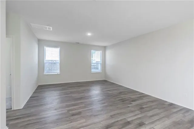 a view of an empty room with wooden floor and window