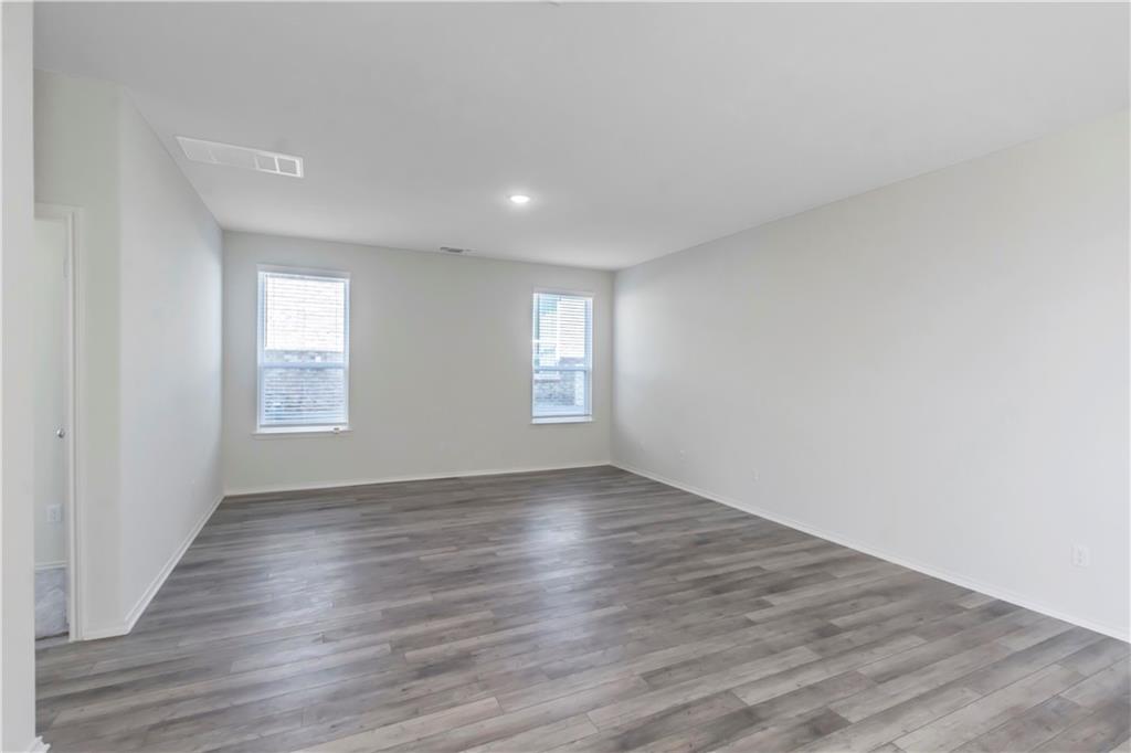 338 Pepperbark Loop Buda, TX 78610 - Photo 8 of 23 a view of an empty room with wooden floor and window