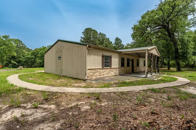 a view of house with yard and trees in the background
