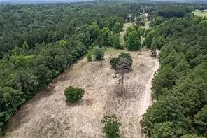an aerial view of residential house with outdoor space and trees all around