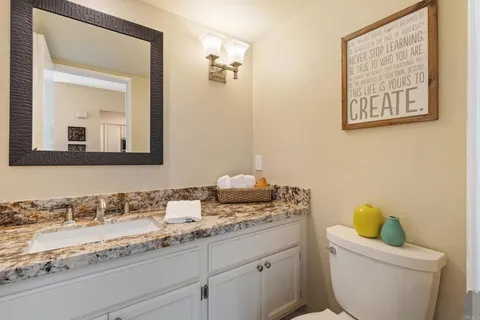 a bathroom with a granite countertop toilet sink and mirror