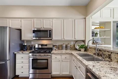 a kitchen with granite countertop a sink stove and refrigerator
