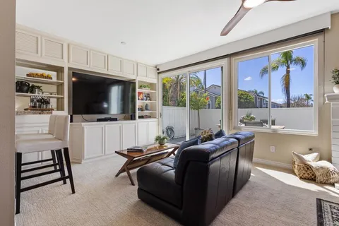 a living room with furniture a flat screen tv and a floor to ceiling window