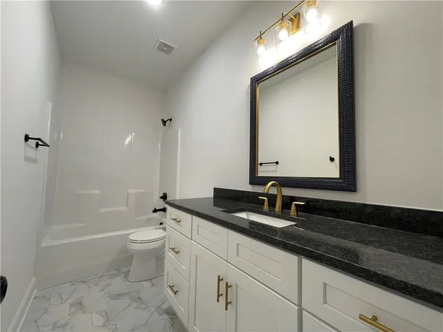 a bathroom with a granite countertop sink a toilet and a bathtub