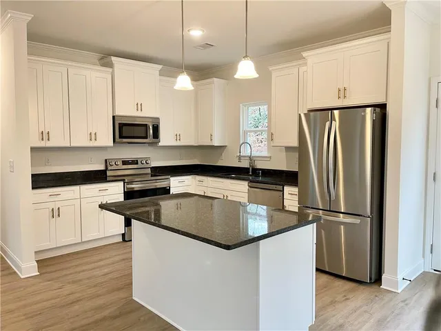 a kitchen with kitchen island granite countertop a refrigerator a sink and white appliances