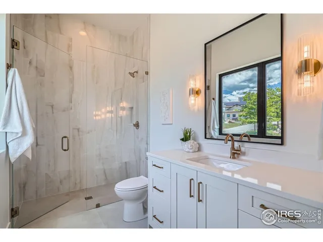 a bathroom with a granite countertop sink toilet a large mirror a shower and a window