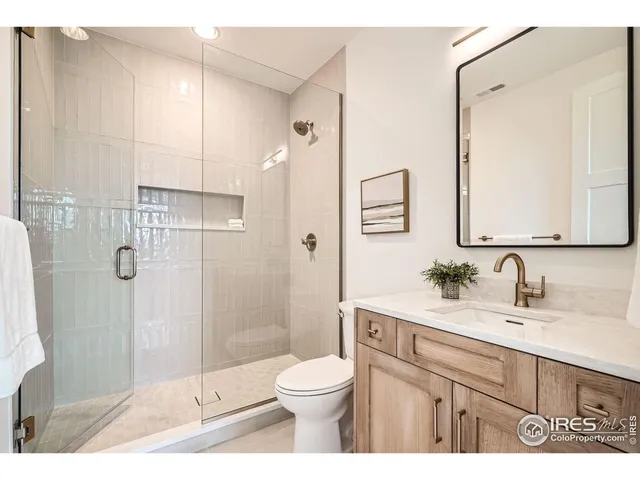 a bathroom with a toilet a sink a glass door a shower and a mirror