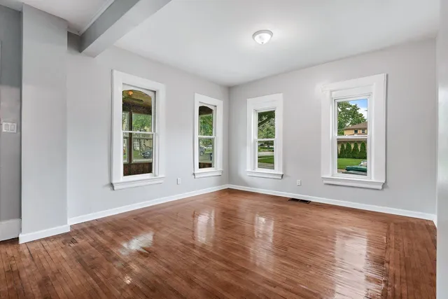 a view of an empty room with wooden floor and windows