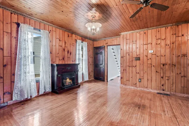a view of an empty room with wooden floor fireplace and a window