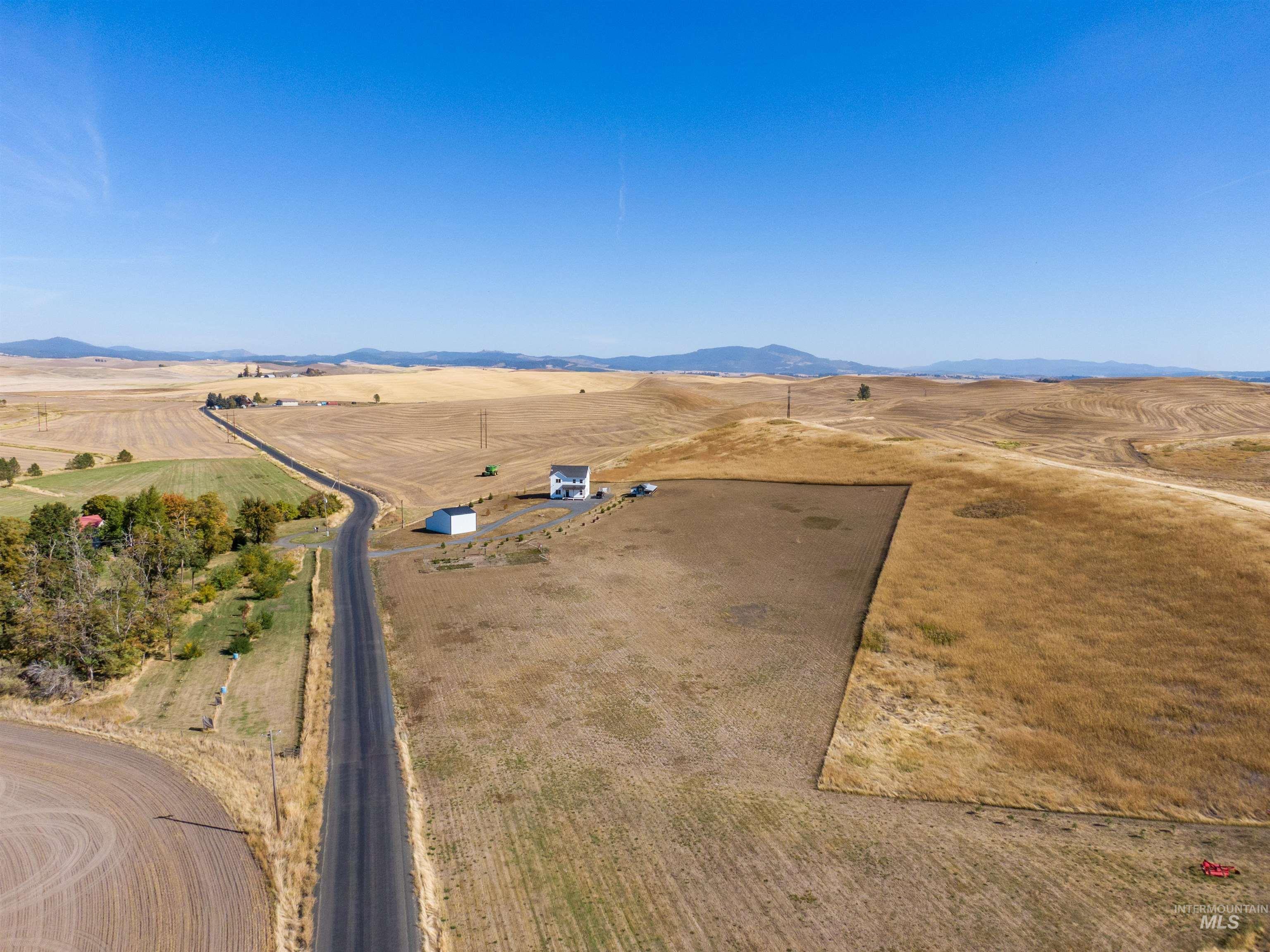 1032 Duffield Flat Road Potlatch, ID 83855 - Photo 48 of 50 Expansive rural property featuring a white two-story residence, a detached outbuilding, and a paved road
