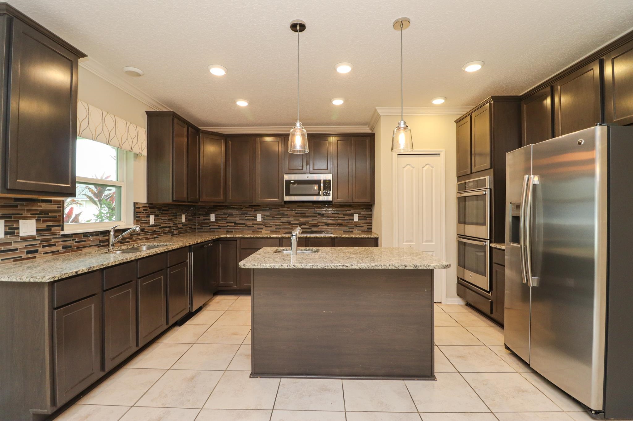 554 Tumbled Stone Way St. Augustine, FL 32086 - Photo 11 of 44 a large kitchen with stainless steel appliances kitchen island granite countertop a refrigerator a oven and a sink
