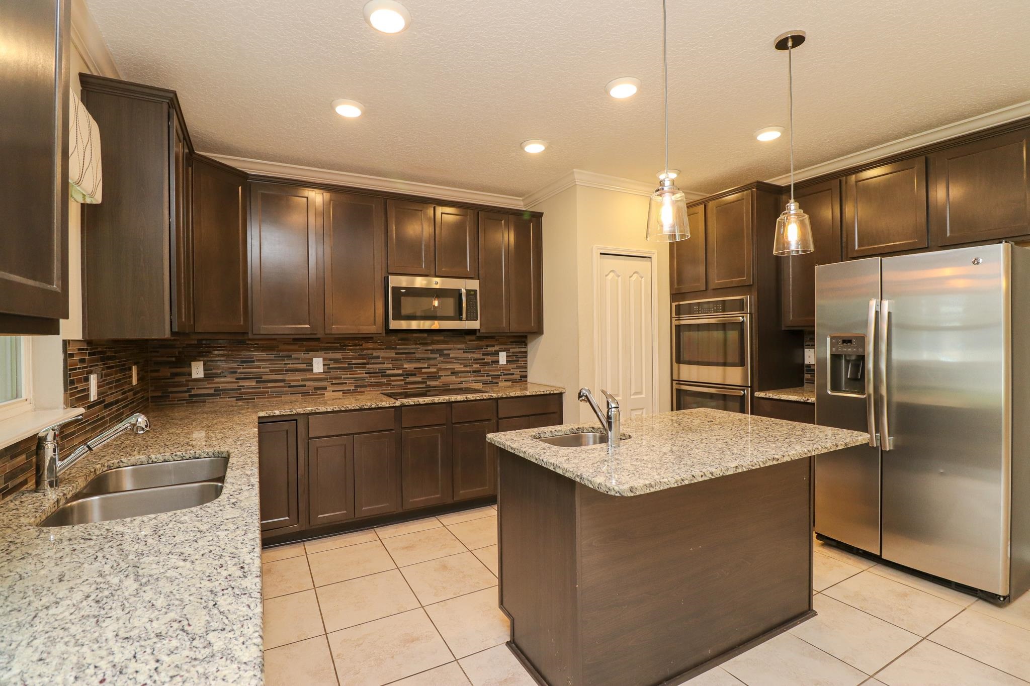 554 Tumbled Stone Way St. Augustine, FL 32086 - Photo 12 of 44 a large kitchen with granite countertop a sink a counter top space appliances and cabinets