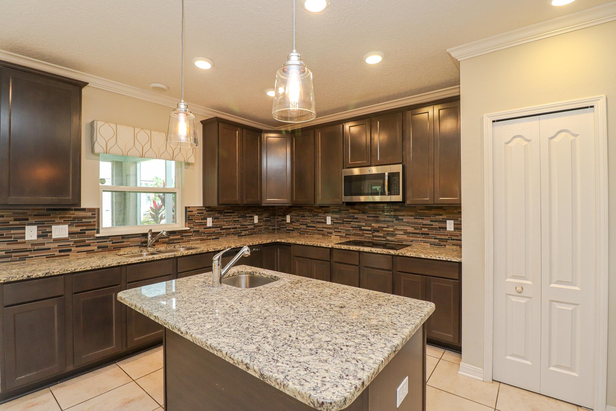 554 Tumbled Stone Way St. Augustine, FL 32086 - Photo 13 of 44 a kitchen with kitchen island granite countertop a sink stove and refrigerator