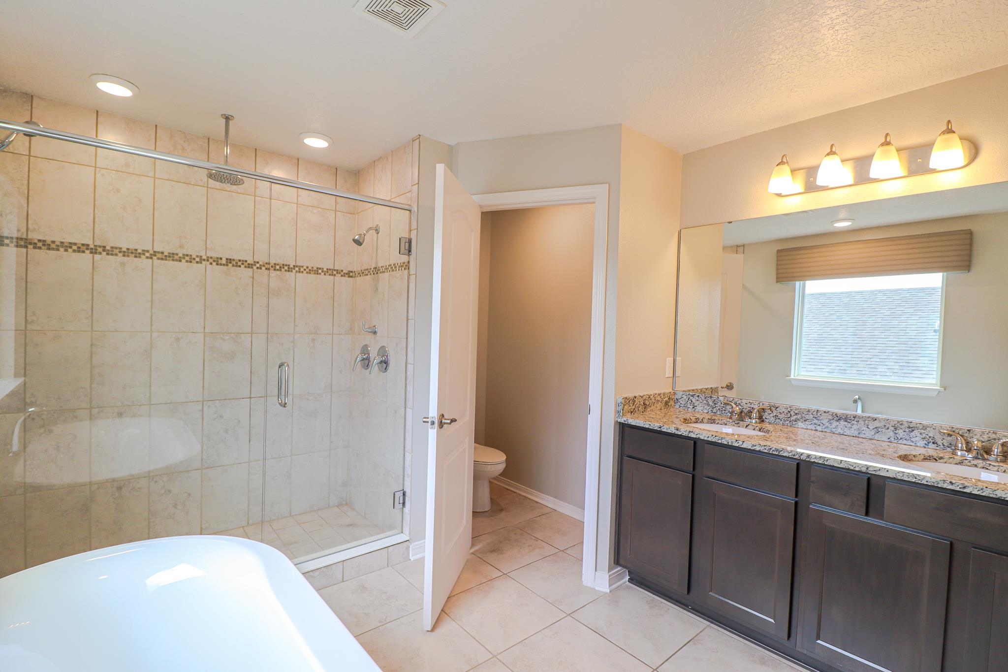 554 Tumbled Stone Way St. Augustine, FL 32086 - Photo 25 of 44 a bathroom with a granite countertop sink a toilet and shower