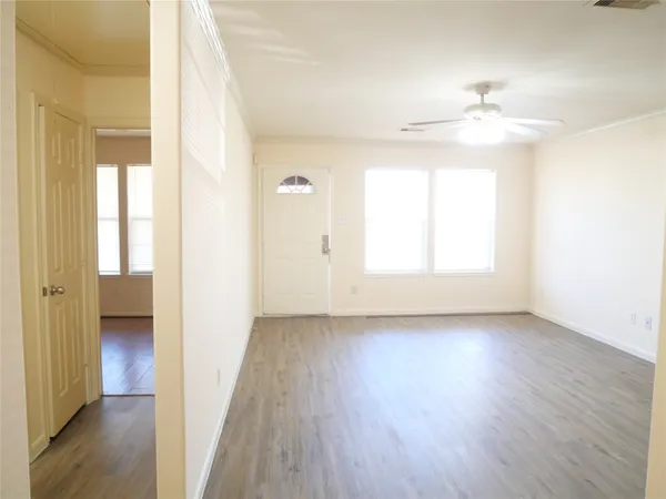 an empty room with wooden floor cabinet and windows