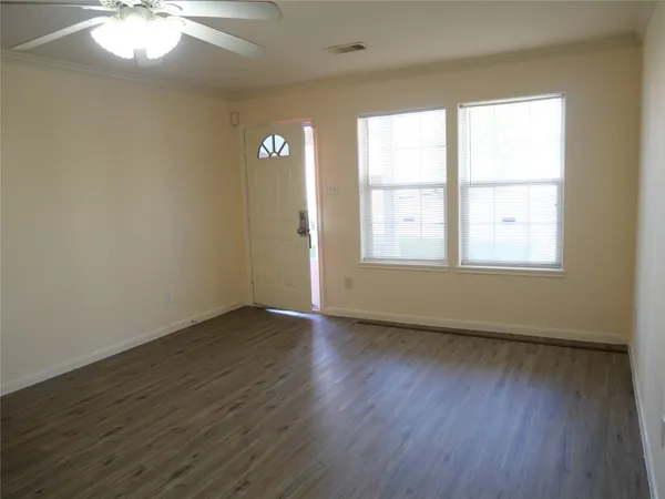 an empty room with wooden floor and windows