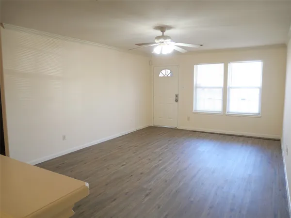 an empty room with wooden floor chandelier fan and windows
