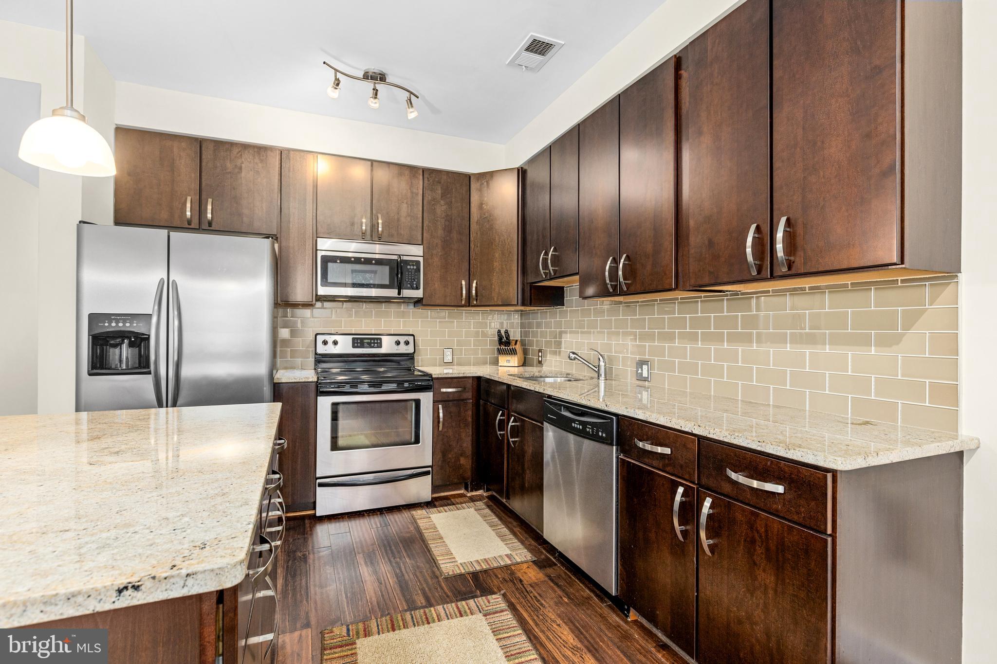 245 15th Street Southeast, Unit 105 Washington, DC 20003 - Photo 6 of 29 a kitchen with stainless steel appliances granite countertop wooden cabinets a stove top oven a sink and dishwasher