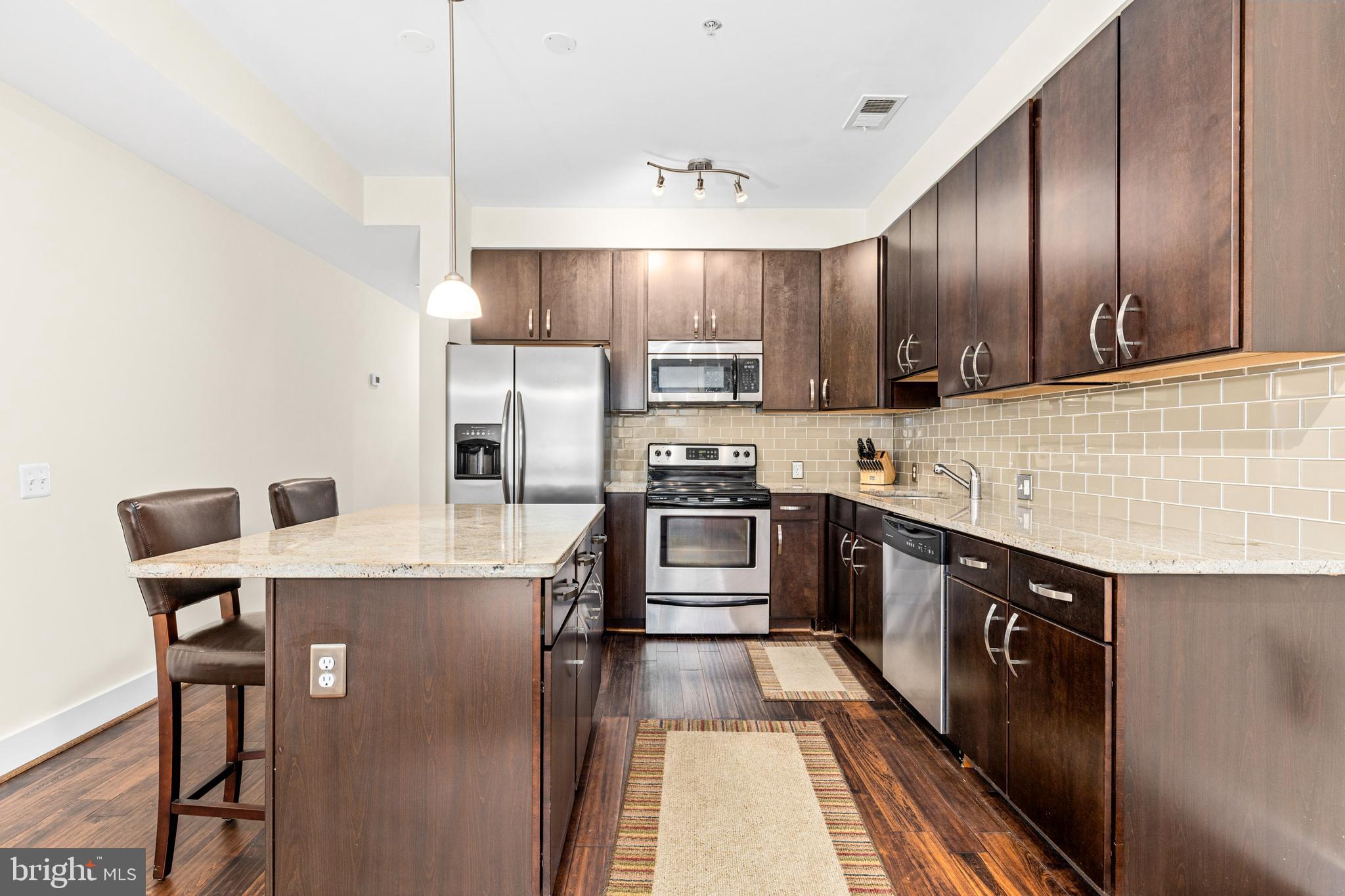 245 15th Street Southeast, Unit 105 Washington, DC 20003 - Photo 7 of 29 a kitchen with stainless steel appliances granite countertop a stove a sink refrigerator and a refrigerator
